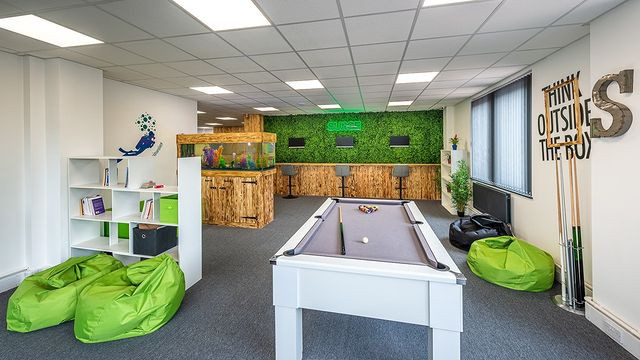 Office space with a pool table bean bags fish tank and plant wall